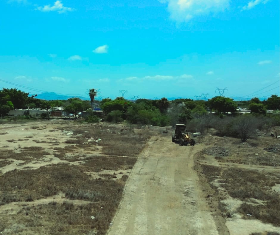 Viviendas y arbolado en los alrededores del predio, sobre camino pavimentado con torres eléctricas de fondo